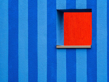 Close-up of red square on striped blue wall