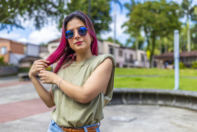 Portrait of smiling young woman wearing sunglasses standing outdoors