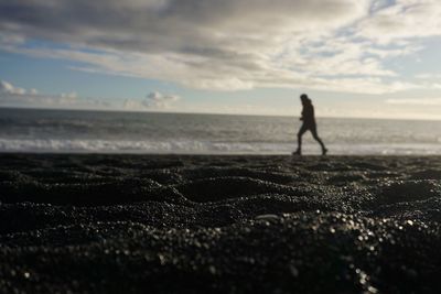 Silhouette people on beach against sky during sunset