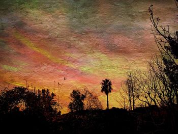 Silhouette trees on field against romantic sky at sunset