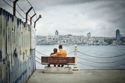 Rear view of men sitting on riverbank