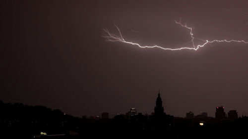 Lightning over illuminated buildings in city at night