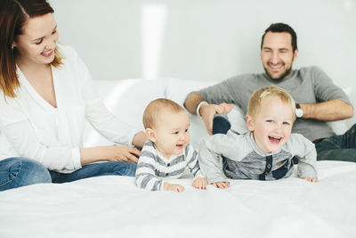 Parents with two small kids playing in bedroom