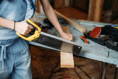 Woman working with wood in workshop. measuring plunk, drilling holes, sewing wood. reuse, reduce