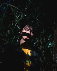 Portrait of young man standing by plants