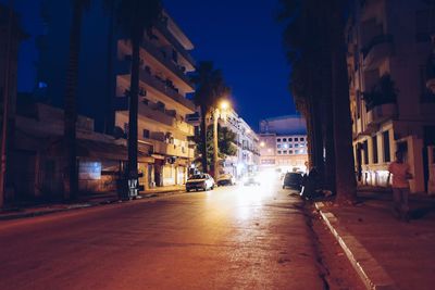 Illuminated street amidst buildings at night