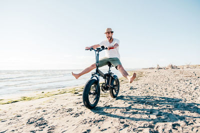 Full length of woman riding bicycle on beach