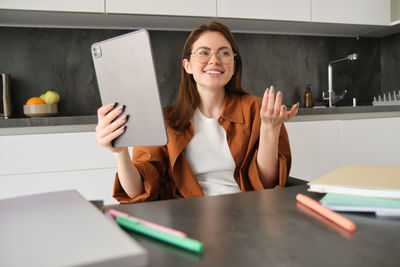 Portrait of young woman using mobile phone at table