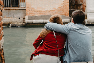 Rear view of couple kissing against canal