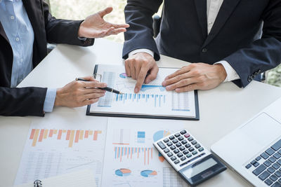 Midsection of business people working on table