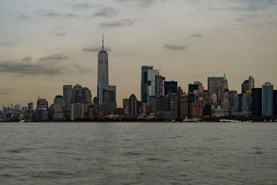 Sea by buildings in city against sky