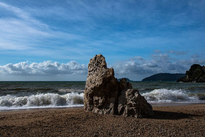 Rock formation on beach against sky