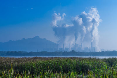 Smoke emitting from chimney on field against sky. lignite coal, coal power plant.