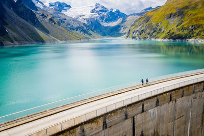 Scenic view of people walking on footbridge over lake