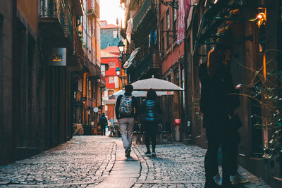 People walking on wet street in city during rainy season