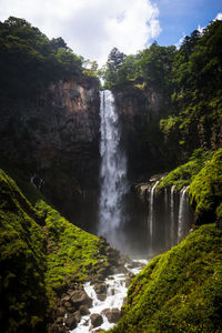 Scenic view of waterfall in forest against sky