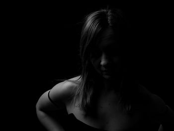 Portrait of woman looking away against black background