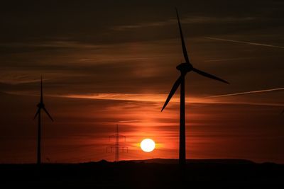 Low angle view of silhouette windmill on field against sky during sunset