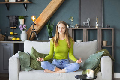 Portrait of young woman sitting on sofa at home