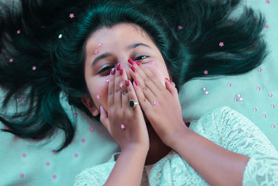 Portrait of woman covering face while lying down on bed