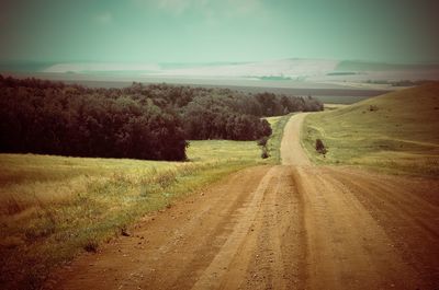 Road amidst field against sky