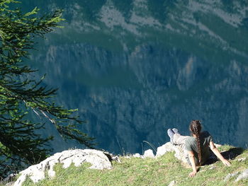 Rear view of woman sitting on mountain during sunny day