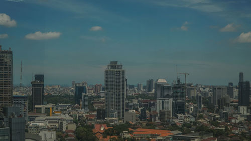 Aerial view of buildings in city against sky