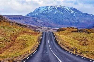 Road amidst snowcapped mountains against sky