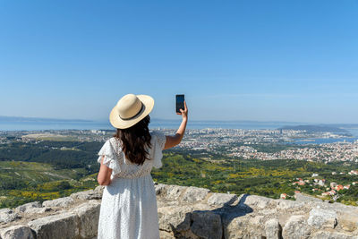 Rear view of woman taking photos of cityscape of split in croatia