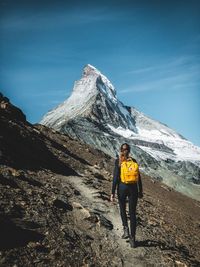 Man standing on snowcapped mountain against sky