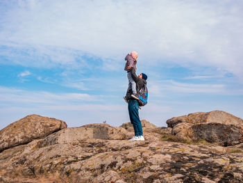 Travelers father daughter walking climbing mountain summit enjoying aerial view cloudy sky together