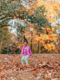 Full length of girl standing by tree during autumn