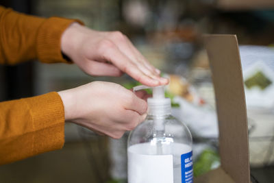 Woman disinfecting hands using sanitizer at store