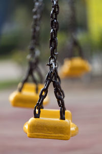 Close-up of empty swings hanging in playground