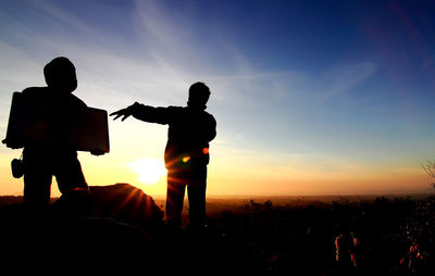 Silhouette people standing on field against sky during sunset