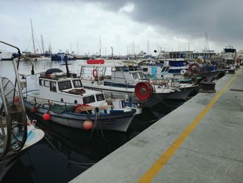 Sailboats moored on harbor against sky