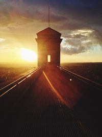 Illuminated building against sky at sunset