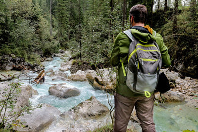 Rear view of man standing on rock in forest