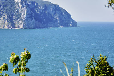 Scenic view of sea by mountain against sky