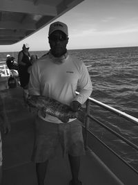 Man holding fish in boat at sea