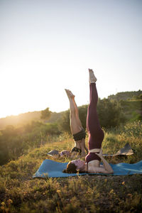 Full length of females exercising on cliff against sky