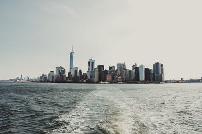 Sea and buildings in city against sky