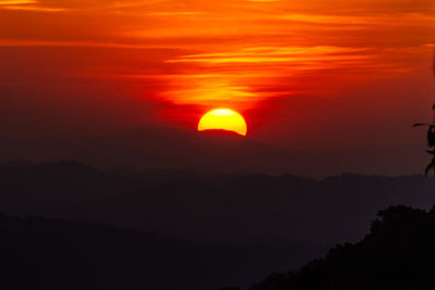 Scenic view of silhouette mountains against orange sky