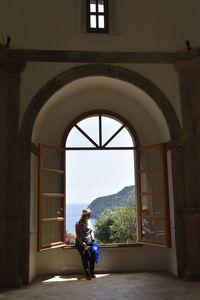 Woman sitting on window of building