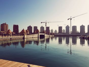 Buildings by river against sky during sunset