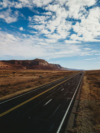 Road leading towards mountain against sky