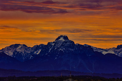 Scenic view of snowcapped mountains against orange sky