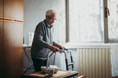 Senior woman holding walker while standing at home