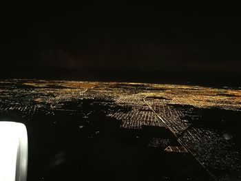 Close-up of illuminated airplane against sky at night