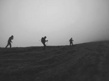 Silhouette of men on landscape against sky